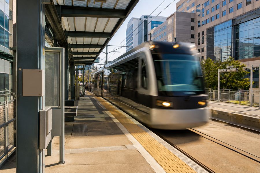Light-rail train arriving at a station platform between medical buildings